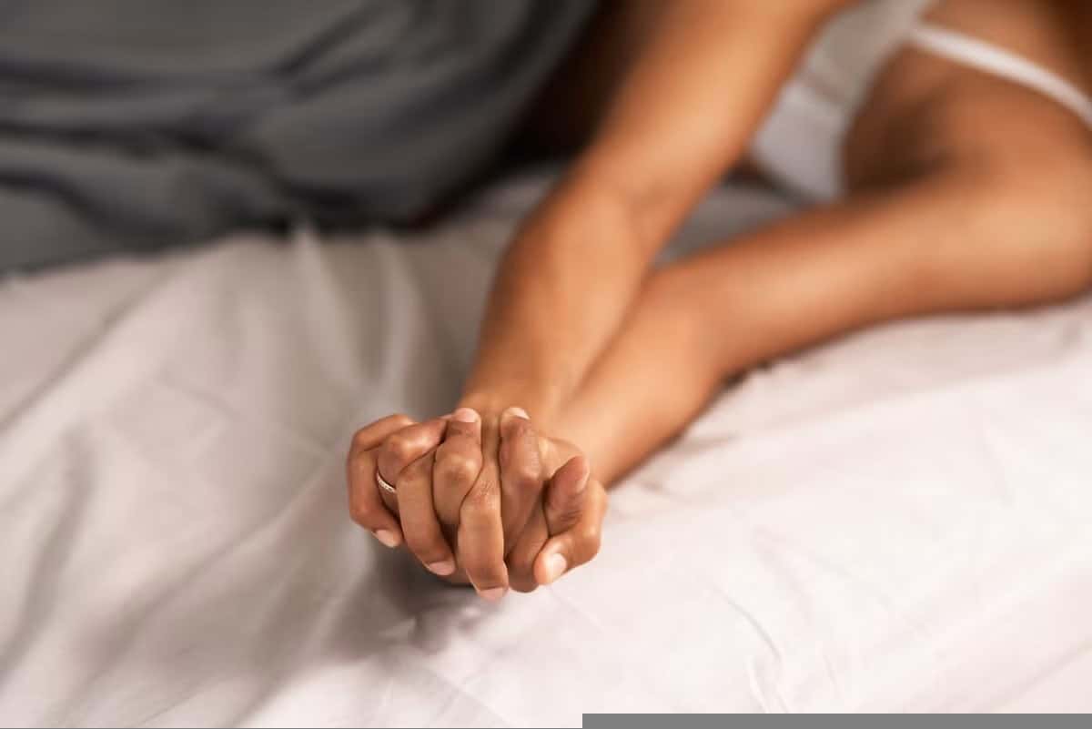 Casal íntimo em posição missionária com toque suave e olhar conectado, representando uma das melhores posições sexuais para aumentar a intimidade do casal.